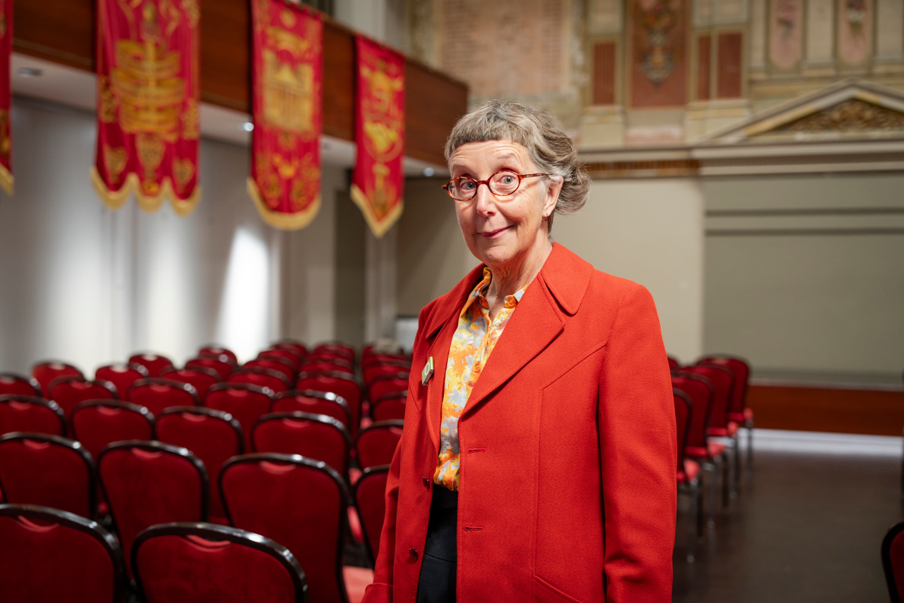 Speaker Robyn Annear in Solidarity Hall within Trades Hall. Decorated with red workers banners.